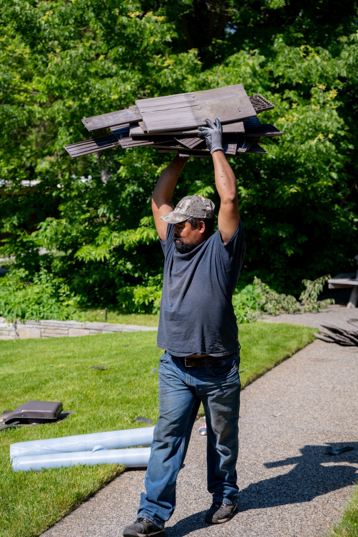 Crew member carrying roofing materials across a residential jobsite